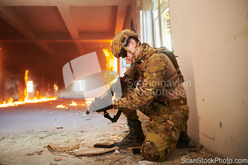 Image of Soldier in action near window changing magazine and take cover