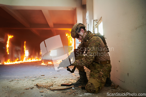 Image of Soldier in action near window changing magazine and take cover