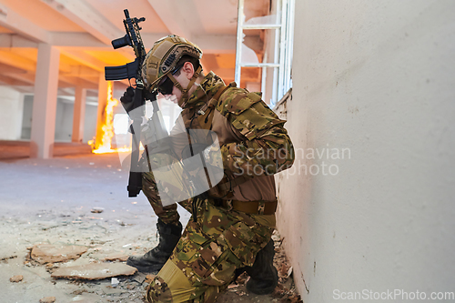 Image of Soldier in action near window changing magazine and take cover