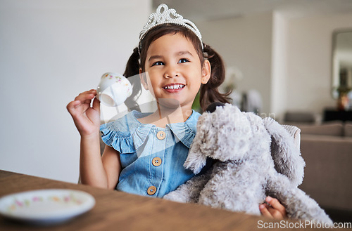 Image of Children, imagination and tea party with a girl playing pretend at a table in her home alone. Kids, happy and game with a young female child drinking from a cup with a teddy bear in her house