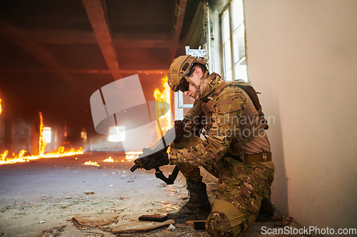 Image of Soldier in action near window changing magazine and take cover