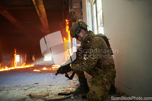 Image of Soldier in action near window changing magazine and take cover