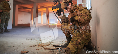 Image of Soldier in action near window changing magazine and take cover