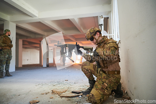 Image of Soldier in action near window changing magazine and take cover