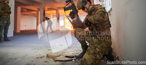 Image of Soldier in action near window changing magazine and take cover