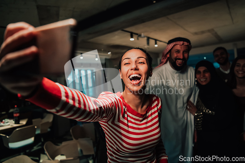 Image of Diverse team of businessmen taking selfie photos on smartphone while in modern office