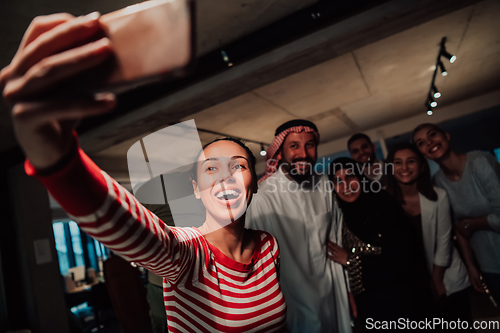 Image of Diverse team of businessmen taking selfie photos on smartphone while in modern office