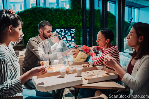 Image of Eating pizza with diverse colleagues in the office, happy multi-ethnic employees having fun together during lunch, enjoying good conversation, and emotions