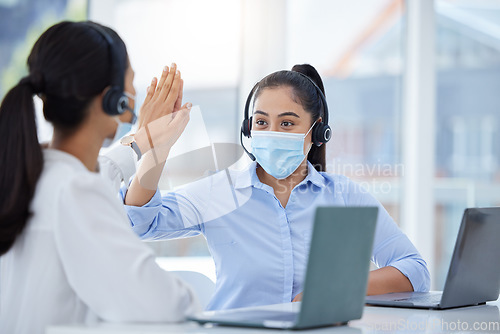 Image of Covid face mask, high five and call center women in customer service laptop support, telemarketing success and b2b sales. Contact us, receptionist or consultants on office tech in covid 19 compliance