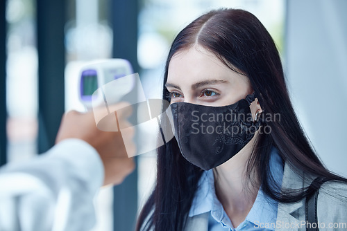 Image of Doctor, covid and thermometer for healthcare scan to test patient temperature or check for fever or symptoms. Businesswoman with corona mask in exam, scanning face with infrared scanner at the office