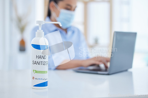 Image of Hand sanitizer, covid and business woman typing on a laptop at desk in her office with face mask. Hygiene, technology and professional employee working on project with computer during corona pandemic