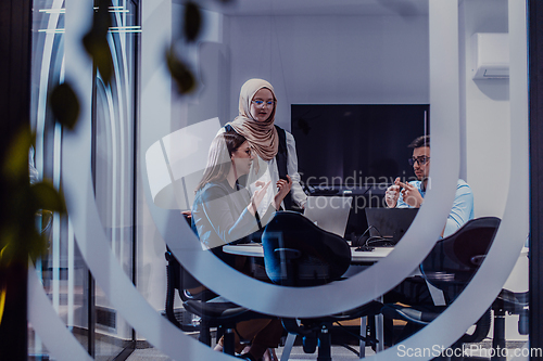 Image of A diverse group of businessmen collaborates and tests a new virtual reality technology, wearing virtual glasses, showcasing innovation and creativity in their futuristic workspace