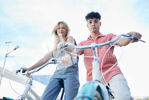 Image of Bike, couple and carbon footprint with a man and woman riding a bicycle outdoor on a blue sky background from below. Portrait, travel and commute with a young male and female cycling on vacation