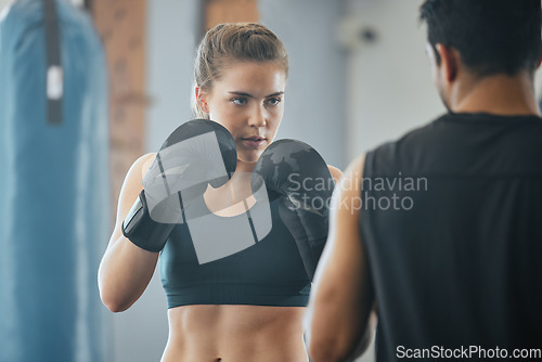 Image of Boxing, exercise and training with a female boxer exercising with her fitness coach or personal trainer in the gym. Fighting, self defense and combat sport with a young woman and her workout partner