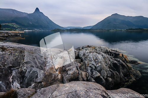 Image of Rocky Shoreline with Water and Mountain Backdrop