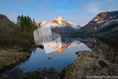 Image of A Serene Lake Surrounded by Snow-Covered Mountains and Trees