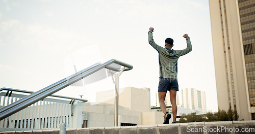 Image of Man, fitness and celebration in city with fist pump for achievement, workout or success in outdoor exercise. Rear view of male person, runner or athlete with hands up in victory for training in town