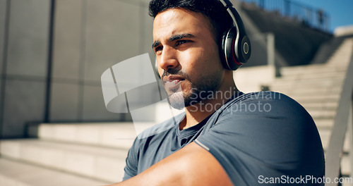 Image of Fitness, music headphones and man on stairs in city, workout and exercise for body health. Radio, serious athlete and person on steps in urban town, listening to audio or podcast, sound and thinking