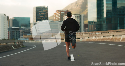 Image of Man, back and running in morning on city, street and bridge for fitness, workout and marathon training. Athlete, person or exercise on South Africa road for wellness, health or triathlon performance