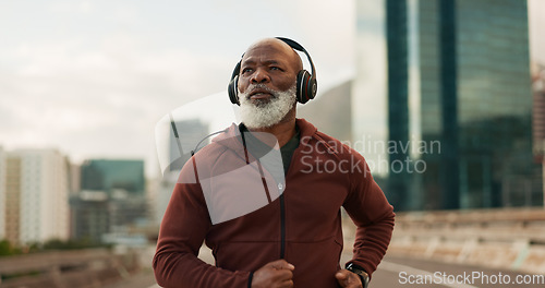 Image of Mature, athlete and running in city with headphones for fitness, workout or marathon training music. Black man, thinking or exercise podcast in South Africa for cardio wellness, health or sport radio