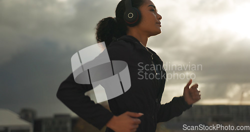 Image of Fitness, music and a woman running in the city for health or cardio preparation of a marathon. Exercise, wellness or sports training and a young runner or athlete listening to audio with headphones