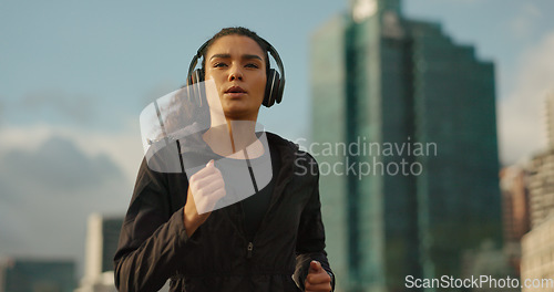 Image of Fitness, music and a sports woman running in the city for health or cardio preparation of a marathon. Exercise, wellness or training and a young runner or athlete listening to audio with headphones