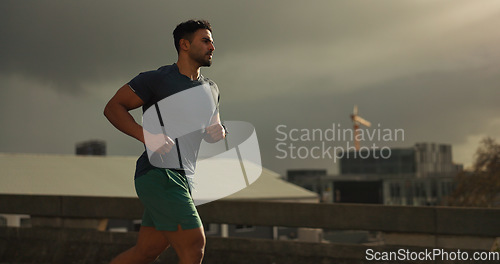 Image of Running, city or man with workout in training, cardio jog or fitness for marathon competition. athlete, wellness or strong body for france with progress, road or health lifestyle and overcast sky