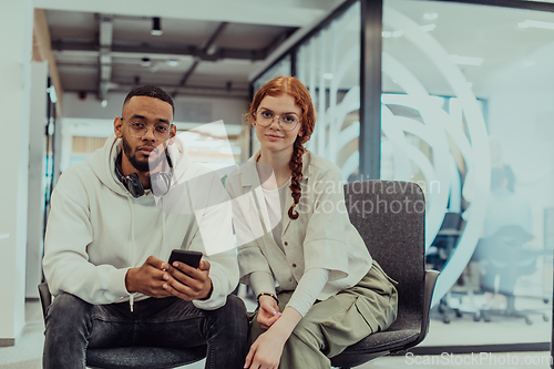 Image of In a modern office African American young businessman and his businesswoman colleague, with her striking orange hair, engage in collaborative problem-solving sessions