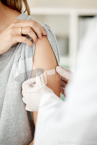 Image of Covid, vaccine and injection with a doctor placing a plaster on the arm of a female patient in the hospital after a booster shot. Closeup of cure and treatment during the corona virus pandemic