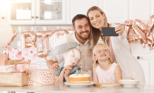 Image of Family birthday party in kitchen, mom photograph on phone camera for social media and mother and father celebrate. Gifts, cake, food and foil balloons at home with dad and twin sisters.