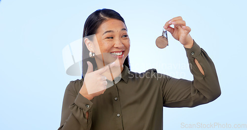 Image of Smile, woman and pointing at keys for real estate, new home and property in studio isolated on a blue background mockup space. Happy person with keychain for house mortgage, apartment rent and moving