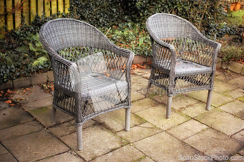 Image of Gardeners corner. Armchairs in a relaxation garden space in a backyard of a home. Decorative outdoor furniture or chairs near ornamental plants. Gardening decor outside of the house in the yard.