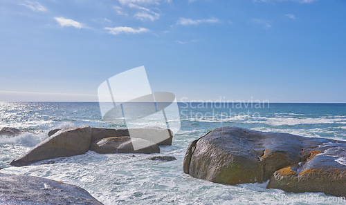 Image of Big rocks in the ocean or sea water with a blue sky background. Beautiful landscape with a scenic view of the beach with boulders on a summer day. Relaxing scenery of the seaside or nature