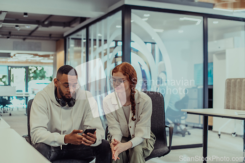 Image of In a modern office African American young businessman and his businesswoman colleague, with her striking orange hair, engage in collaborative problem-solving sessions