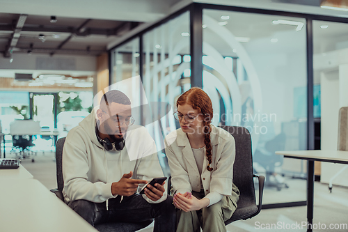 Image of In a modern office African American young businessman and his businesswoman colleague, with her striking orange hair, engage in collaborative problem-solving sessions