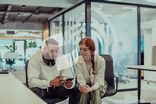 Image of In a modern office African American young businessman and his businesswoman colleague, with her striking orange hair, engage in collaborative problem-solving sessions