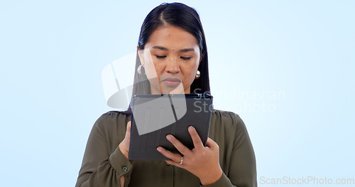 Image of Business, woman and tablet in studio for research, networking and planning with serious expression on blue background. Person, touchscreen or technology for scrolling on website or corporate search