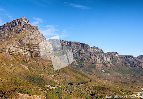 Image of Landscape of mountains on a blue sky background with copy space. Beautiful view of mountain outcrops with hills covered in green grass, trees and bushes on a popular landmark location in South Africa