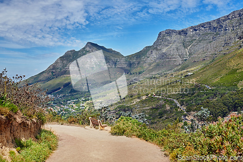 Image of Beautiful hiking trail on the mountains with a blue cloudy sky background. A zen, nature landscape with a bench overlooking green lush hills and roads for traveling on Table Mountain, South Africa