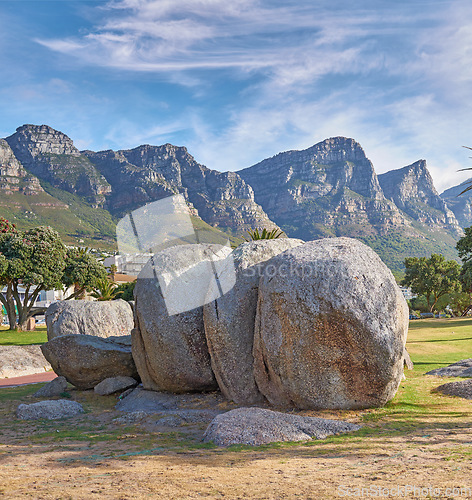 Image of Landscape view of mountains beach rocks in famous travel or tourism destination with lush trees and grass. Scenic Twelve Apostles with blue sky and clouds in Camps Bay, Cape Town, South Africa