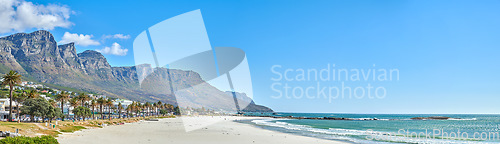 Image of Quiet and calm beach and ocean with sandy shore and palm trees. Scenic seascape of the Twelve Apostles mountain under a blue sky in Cape Town. A beautiful holiday destination for travel and tourism