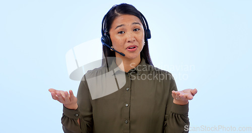 Image of Portrait, customer service and support with an asian woman consulting in studio on a blue background. Contact us, crm or telemarketing with a young call center employee talking on a headset for help