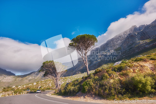Image of Countryside road by winding through the mountains on a scenic day. Street on the mountain with green trees and cloudy blue sky copy space. A nature path for traveling or hiking in Cape Town