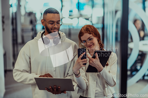 Image of In a modern office African American young businessman and his businesswoman colleague, with her striking orange hair, engage in collaborative problem-solving sessions