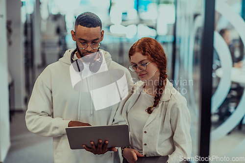 Image of In a modern office African American young businessman and his businesswoman colleague, with her striking orange hair, engage in collaborative problem-solving sessions