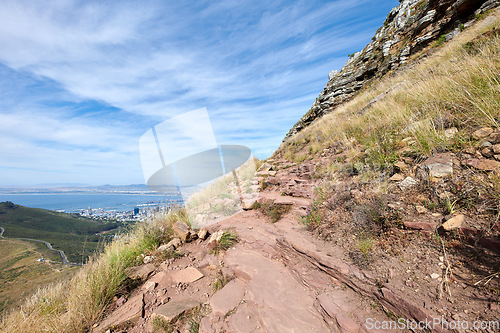 Image of Scenic of a rocky mountain slope with view of a coastal city by the sea and cloudy sky background with copyspace. Rugged landscape on a cliff with hiking trail on Lions Head, Cape Town, South Africa