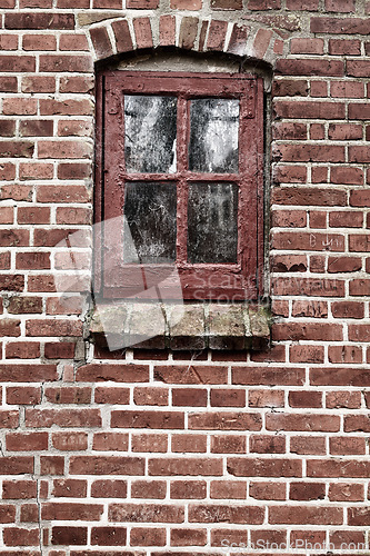 Image of Old dirty window in a red brick house or home. Ancient casement with red wood frame on a historic building with clumpy paint texture. Exterior details of a windowsill in a traditional town or village