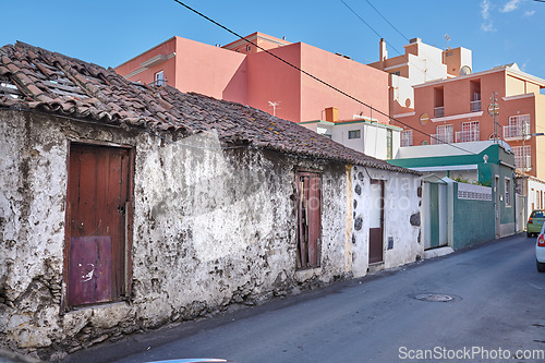 Image of Exterior of decaying brick buildings with peeling paint in a street of Santa Cruz de La Palma. Architectural details of an abandoned rustic property with damaged and aged doors or entrances outside