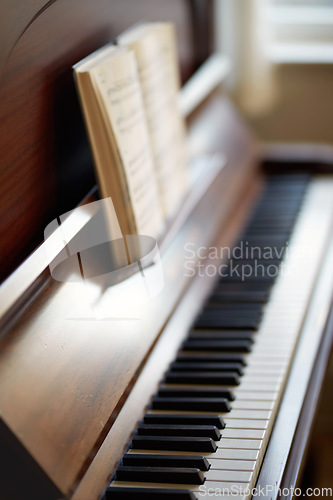 Image of The piano. A vintage grand piano with a book of sheet music for education. An antique and classic keyboard is used to develop skills. A classical wooden musical instrument for practising music.