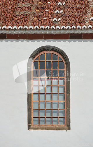 Image of Architecture of a grey wall with an arched window outside. Exterior texture details of an old rustic residential building or church with vintage wooden windows discovered in Santa Cruz de La Palma